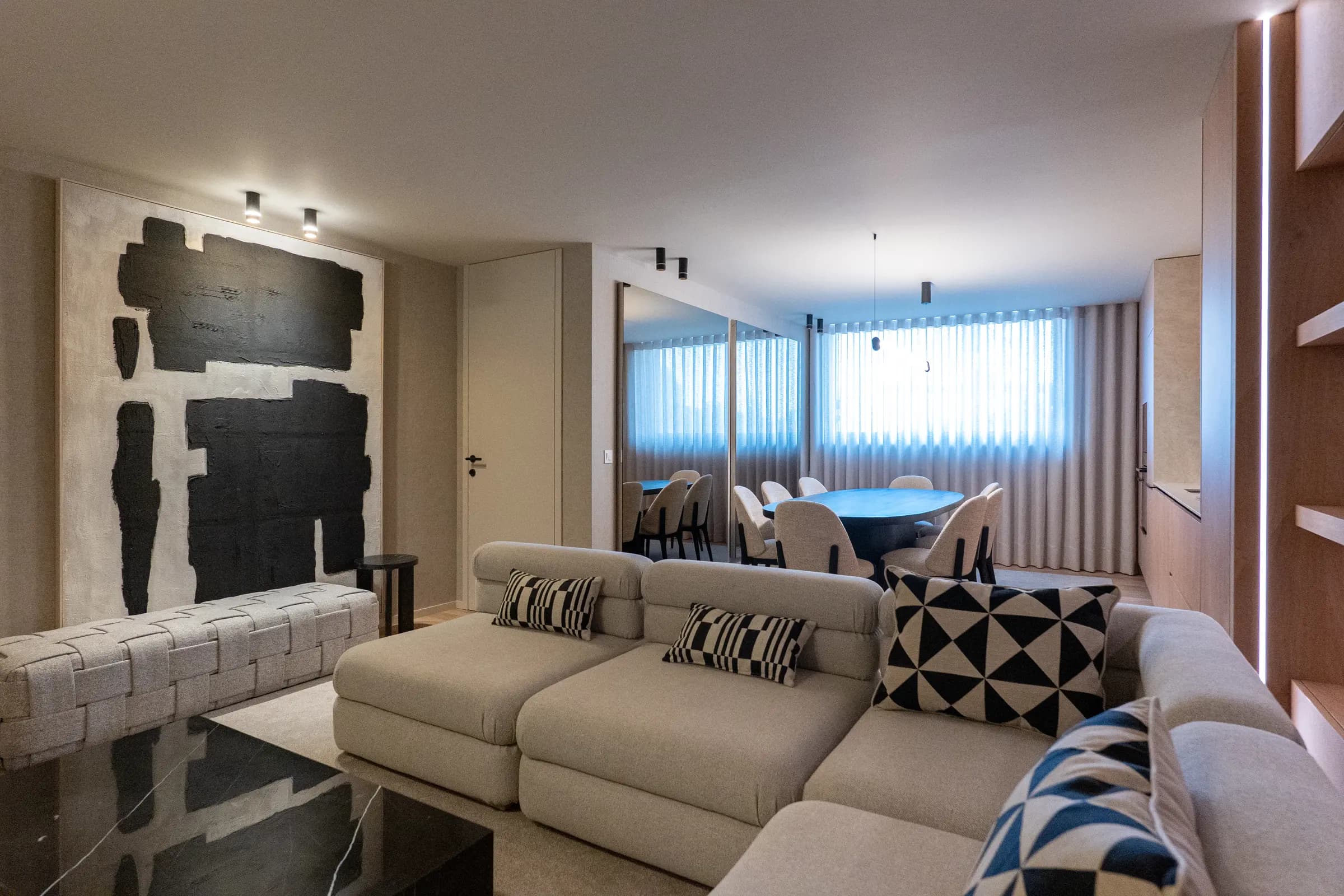 Sala de um apartamento do Metro Village, com sofá claro e mesa de jantar junto às cortinas